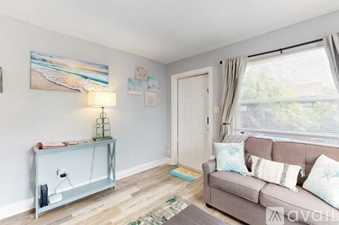 A living room with a grey couch and a painting on the wall.