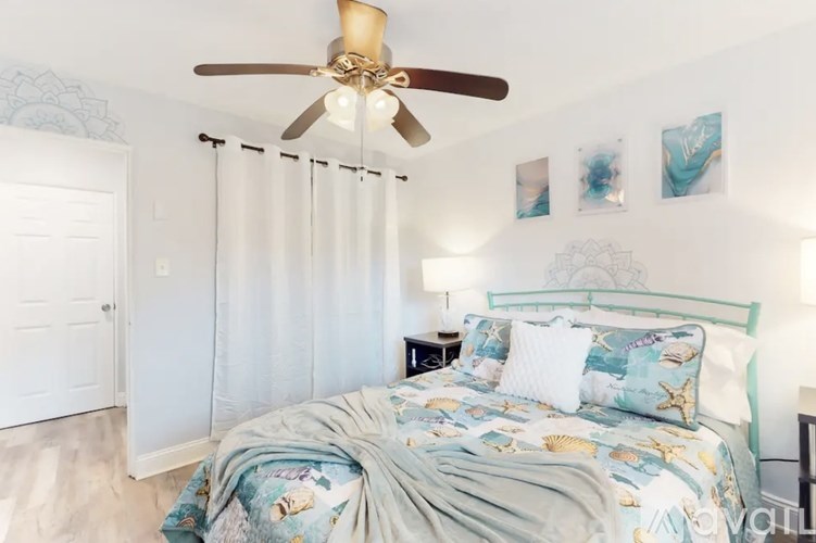 A bedroom with a bed, a ceiling fan, and a nightstand.