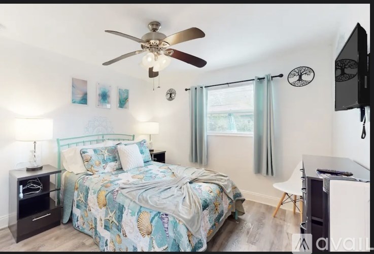A bedroom with a bed, a ceiling fan, and a television.