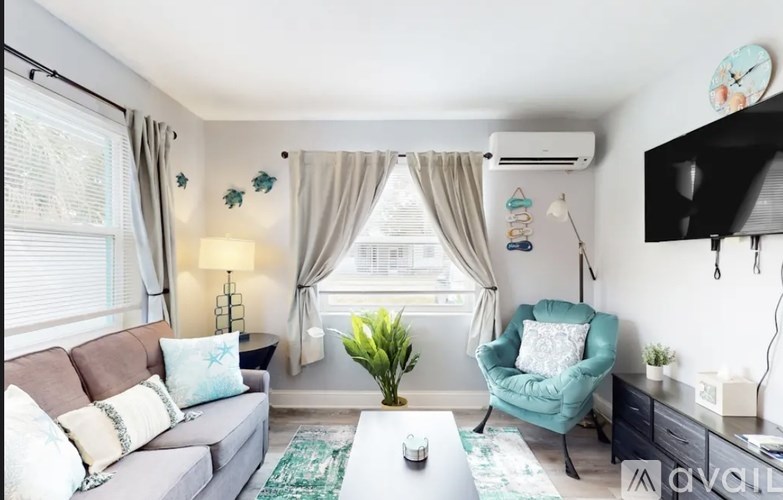A living room with a grey couch, a green armchair, a white coffee table, and a TV on the wall.