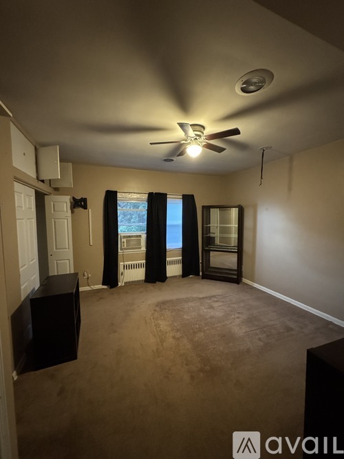 A room with a ceiling fan and a window with curtains.