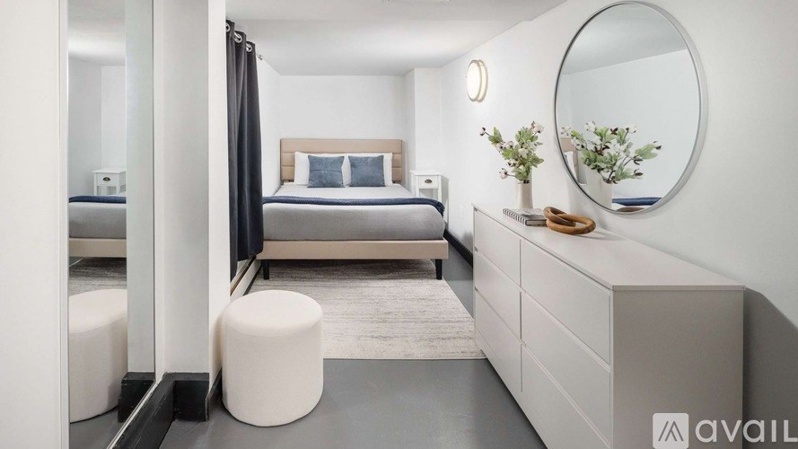 A modern bedroom with a bed, nightstand, and a round mirror on the wall.