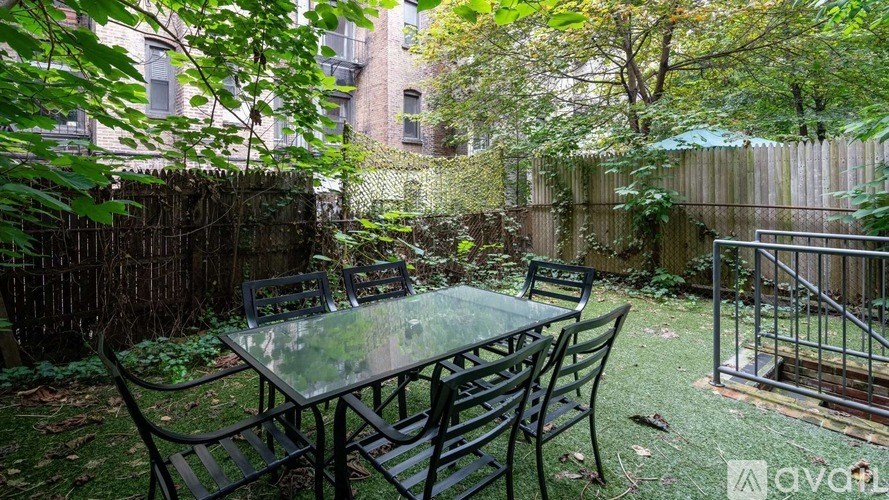 A patio with a table and chairs surrounded by a fence and trees.