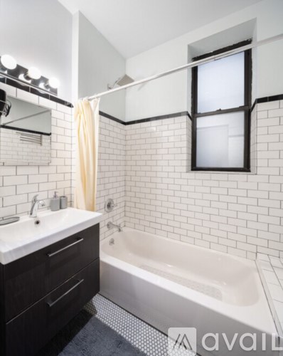 A white tiled bathroom with a white bathtub and a white sink.