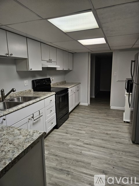 A kitchen with white cabinets and a black stove top oven.