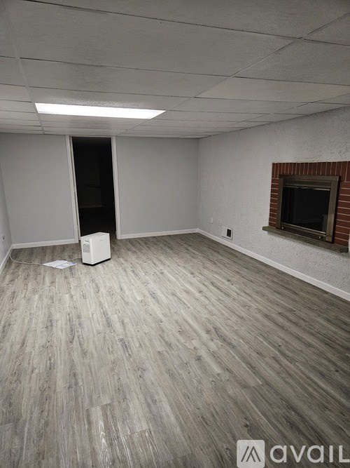 A room with a white wall and a fireplace with a brick surround.