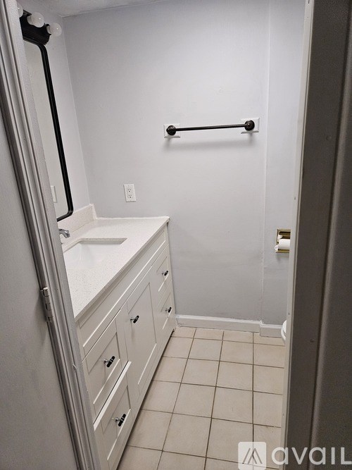 A white bathroom with a white tub and a white towel rack.