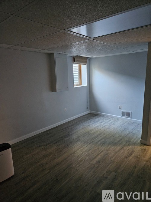 A room with a window and a trash can.