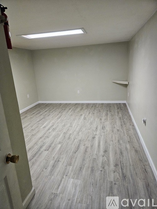 A room with wooden flooring and white walls.