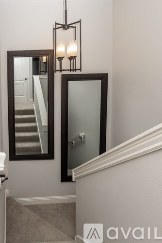 A staircase with a mirror and a chandelier.