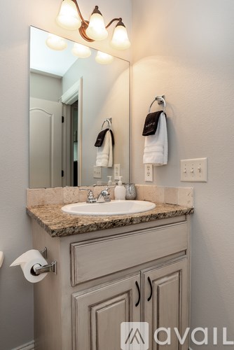 A bathroom with a sink, mirror, and towel rack.