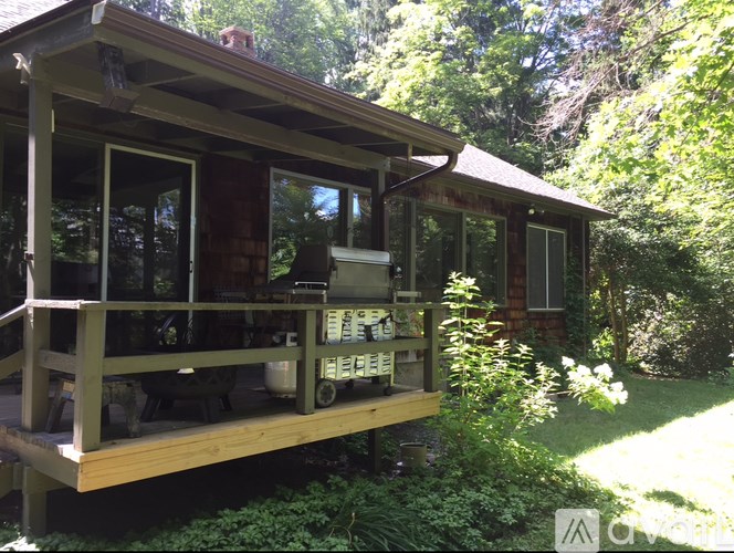A wooden cabin with a porch and a grill on it.
