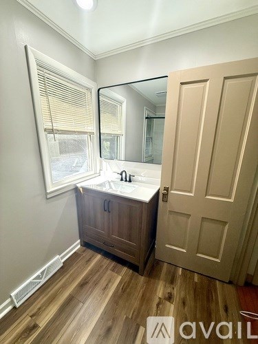 A bathroom with a wooden floor, a sink, and a mirror.
