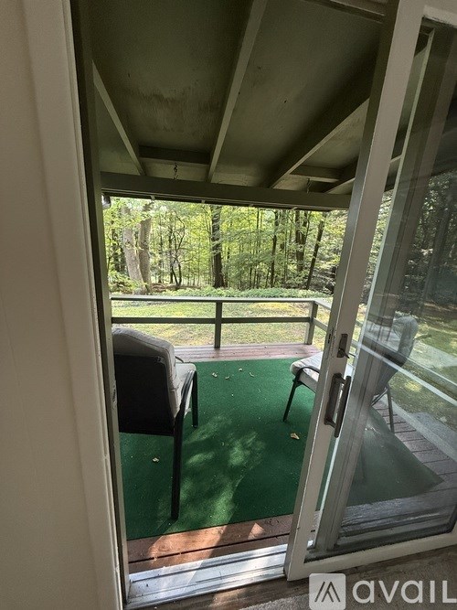 A glass door leading to a balcony with a green mat and a chair.