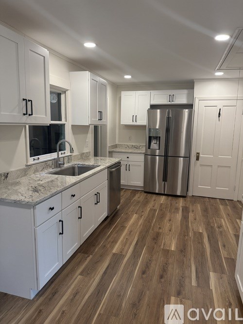 A kitchen with white cabinets and a marble countertop.