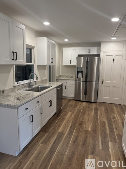 A kitchen with white cabinets and a marble countertop.