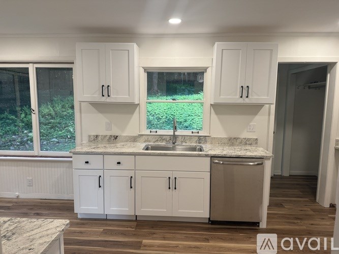 A kitchen with white cabinets and a marble countertop.