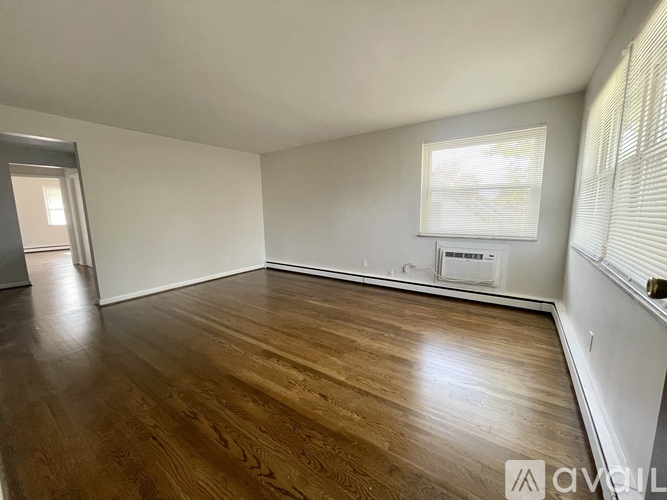 A room with wooden floors and a window with blinds.
