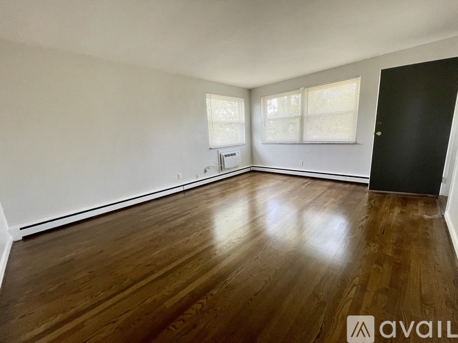 A spacious room with wooden floors and white walls.