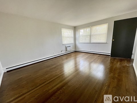 A spacious room with wooden floors and white walls.