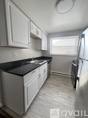 A kitchen with white cabinets and a black countertop.