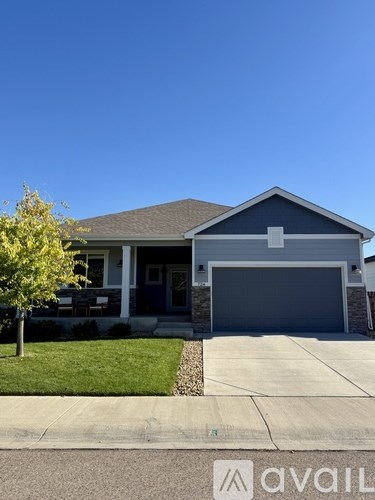 A house with a garage door and a tree in front.