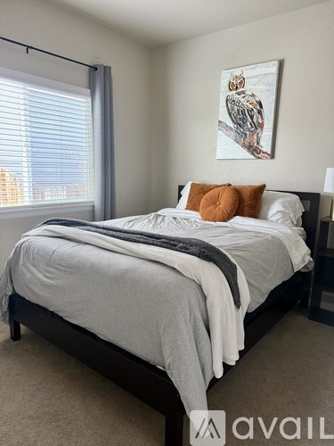 A bedroom with a bed, pillows, and a painting on the wall.