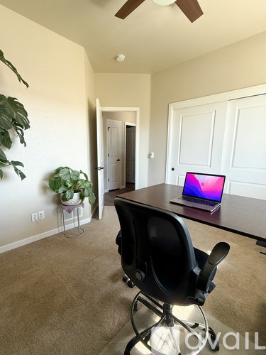 A room with a black chair and a laptop on a desk.