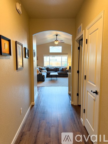 A hallway with a couch and chairs in the background.