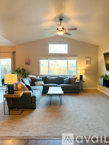 A living room with a grey couch, a wooden coffee table, and a ceiling fan.