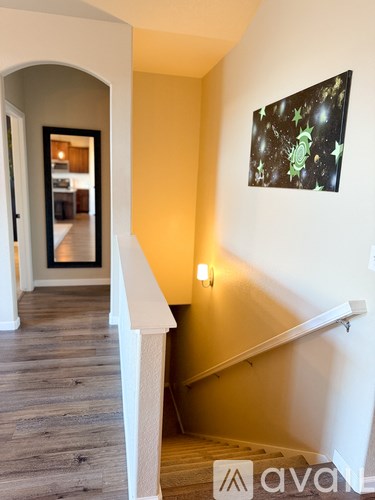 A hallway with a staircase and a painting on the wall.
