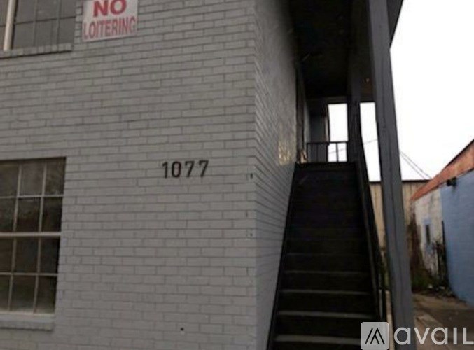A building with a staircase leading to the second floor and a sign that says "NO LOITERING".