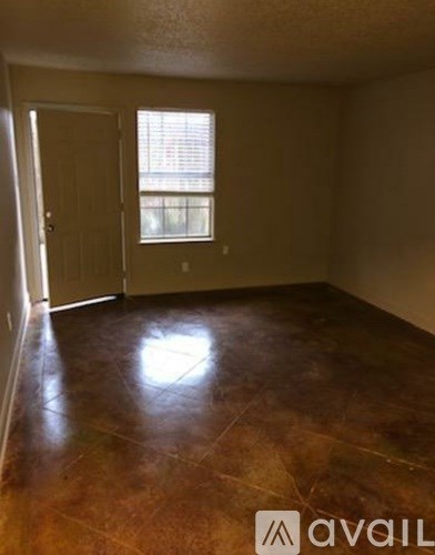 A room with brown flooring and a window with blinds.