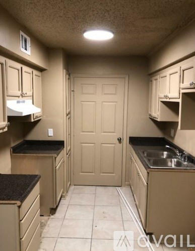 A kitchen with a sink, cabinets, and a door.