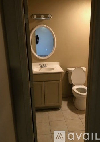 A bathroom with a toilet, sink, and mirror.