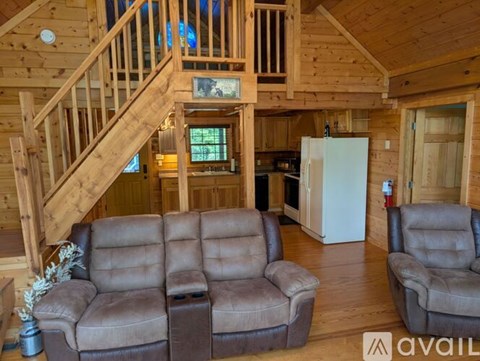 A living room with a brown couch and a staircase.