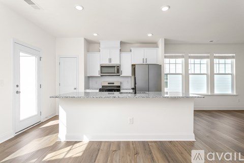 A kitchen with white cabinets and a wooden floor.