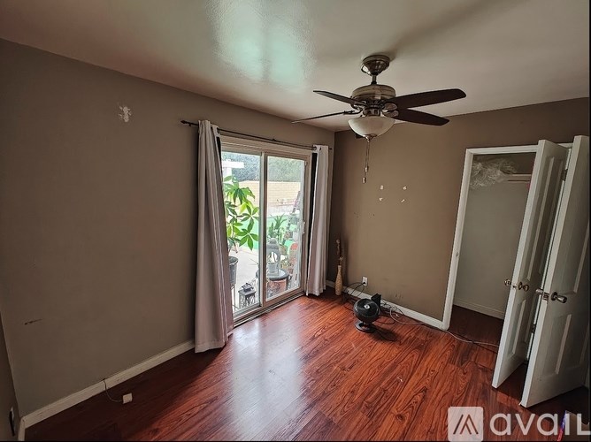 A room with a ceiling fan and a window with curtains.