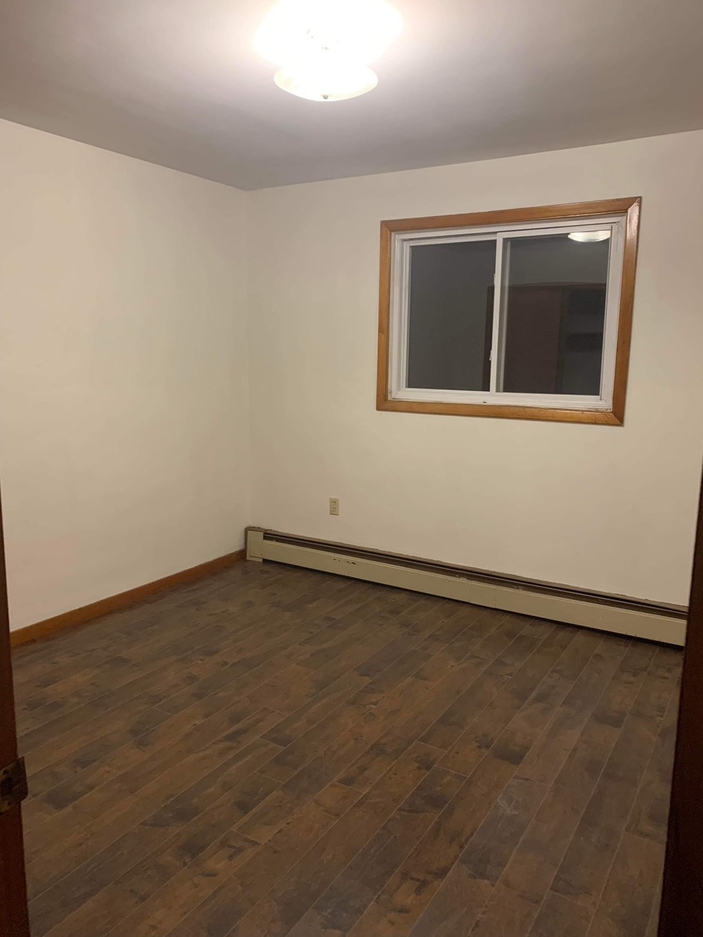 A room with a window and a heater on the wall.