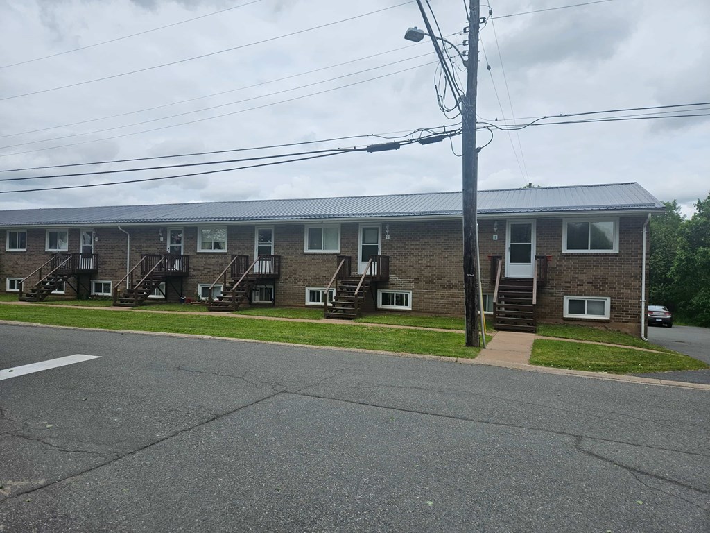 A building with a grey roof and a white car parked in front.