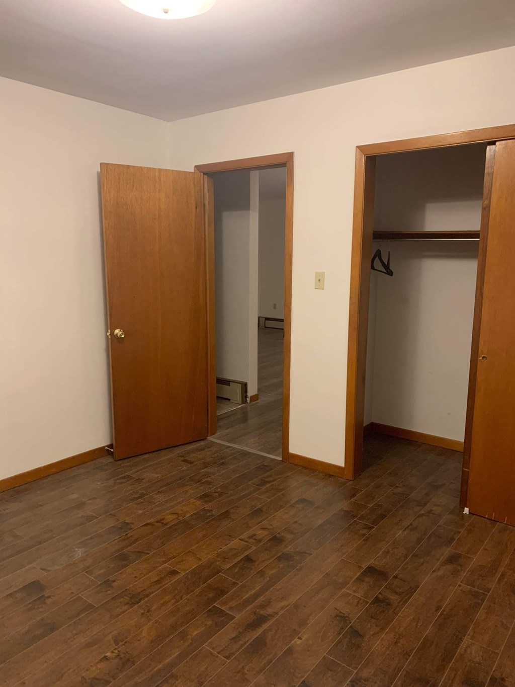 A room with a wooden floor and two open doors.