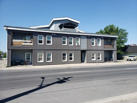 A grey building with a white car parked in front.