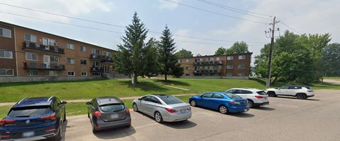 A parking lot with cars and apartment buildings in the background.