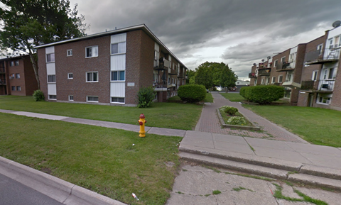 A street view of a residential area with apartment buildings, a fire hydrant, and a sidewalk.