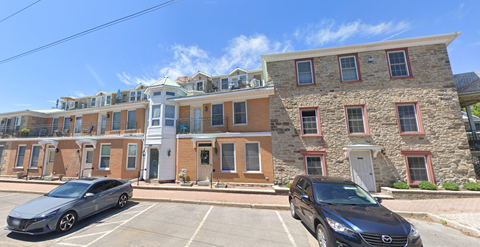 Two cars are parked in front of a building with a stone facade.