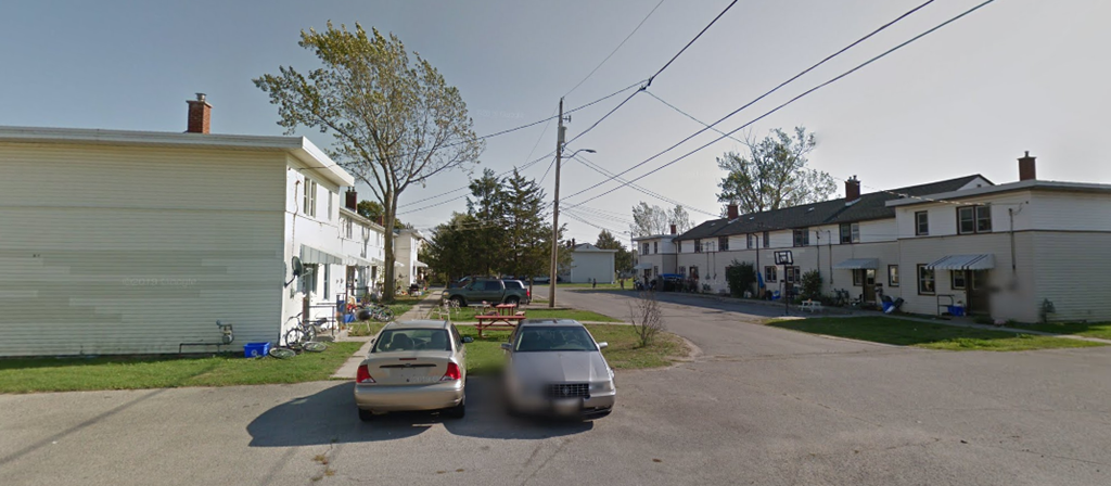 A street with cars and houses on both sides.
