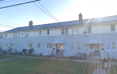 A white building with a blue roof and a bicycle parked in front.