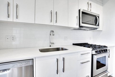 A modern kitchen with white cabinets and stainless steel appliances.