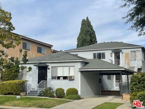 A house with a grey roof and a white fence in front.