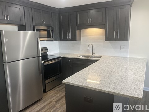 A kitchen with a stainless steel refrigerator and dark wood cabinets.